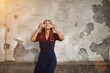 © oleg_chumakov - Woman in dress with white headset. Lady posing on old wall backdrop. Listen music and street style concept, copy space