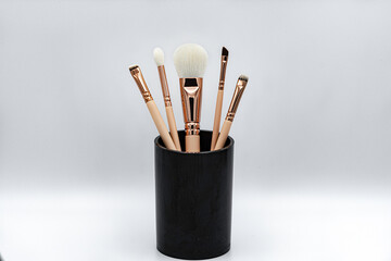 makeup brushes in a black glass. White background.