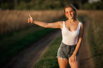 beautiful young female on the road hitchhiking