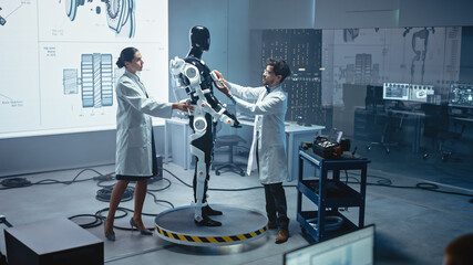 Poster - In Robotics Development Laboratory: Chief Female Engineer and Top Male Scientist Work on a Bionics Exoskeleton Prototype. Designing Powered Exosuit to Help Disabled People, Hard Labor Workers