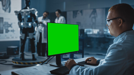 Wall Mural - In Development Laboratory: Chief Analyst Uses Computer with Green Screen Template, Scientists and Engineers Work on a Robotics Exoskeleton Prototype. Designing Exosuit to Help Disabled People