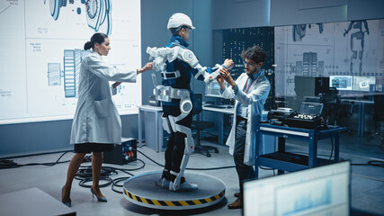 Poster - In Robotics Development Laboratory: Engineers and Scientists Work on a Bionics Exoskeleton Prototype with Person Testing it. Designing Wearable Exosuit to Help Disabled People, Warehouse Workers