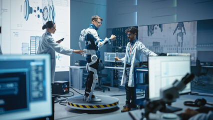 Poster - In Robotics Development Laboratory: Engineers and Scientists Work on a Bionics Exoskeleton Prototype with Person Testing it. Designing Wearable Exosuit to Help Disabled People, Warehouse Workers