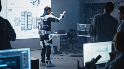 Poster - In Development Laboratory: Engineers and Scientists Look at Robotics Exoskeleton Prototype Presentation with Person Testing it, Moving and Performing. Designing Wearable Exosuit to Help People