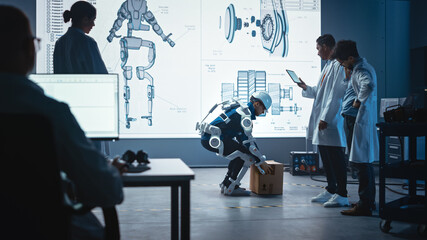 Poster - In Development Laboratory: Engineers Look at Robotics Exoskeleton Prototype Presentation with Person Testing it, Lifting Heavy Carboard Box. Designing Wearable Exosuit to Help Warehouse Workers