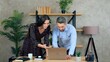© viacheslav - Smiling man and woman employees working together in an office preparing presentation for meeting. Manager shows report to businesswoman on laptop computer
