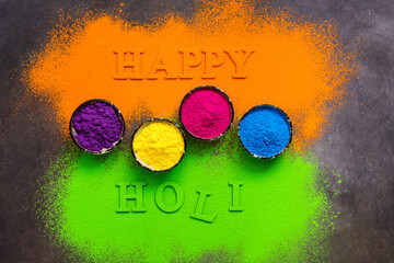 Wall Mural - Colored powder in bowls for holi festival. Happy holi lettering. Beautiful bright background from colorful powder. Top view.