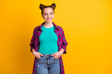 Canvas Print - Photo of attractive charming teen lady two funny buns hold hands pockets good mood look side empty space wear casual plaid long magenta shirt jeans isolated yellow bright color background