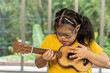 Autistic, Autism or Down Syndrome children girl is playing the ukulele. Concept disabled child learning in school.