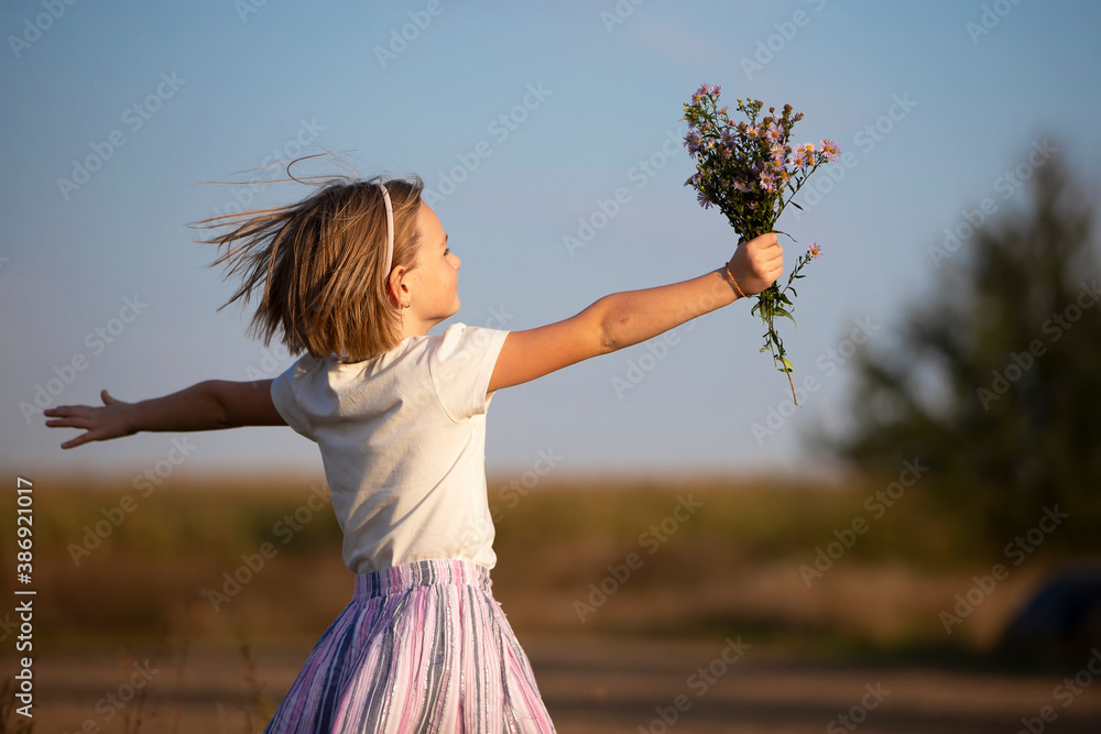 Beautiful little girl in the meadow with a bouquet of flowers. A child ...