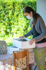 Sticker - Woman wearing mask at home. She ordered fresh fish online in covid pandemic