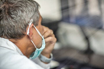 Poster - Male doctor wearing mask in covid-19 department looking at patient x-ray on the computer screen