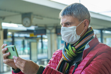 Canvas Print - Man with health mask using smartphone at empty railway station in covid pandemic