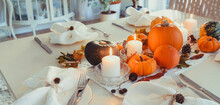 Festive Table Setting For Thanksgiving Family Home Dinner. Fall Composition With Decorative Pumpkins, Nuts, Cones, Fallen Leaves, And Candles In Light Interior. Natural Autumn Decor. Selective Focus