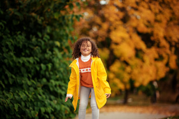 Wall Mural - Cute afro girl smiling broadly outdoors and enjoying autumn day in park.