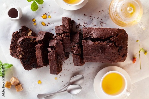 Fotomural chocolate loaf cake with walnuts and prunes on the table with green tea