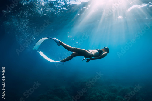Plakaty nurkowanie  wolna-kobieta-nurek-z-bialymi-pletwami-sunie-pod-woda-z-niesamowitymi-promieniami-slonecznymi-freediving-pod-woda