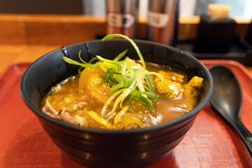 Japanese curry rice with beef in a black bowl on table with nature light through the window.