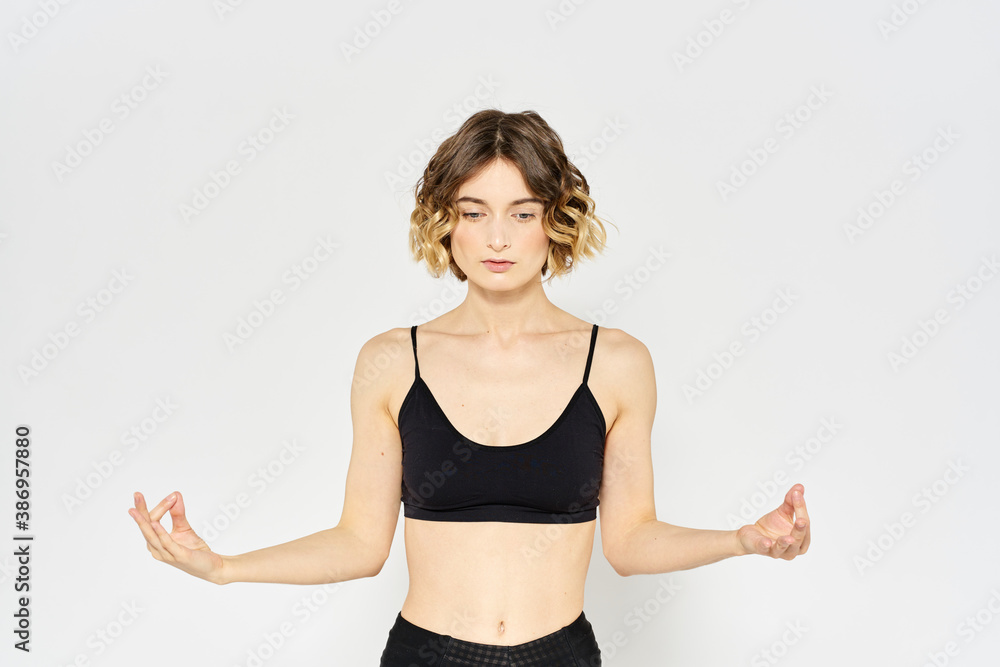 sporty woman in black jeans and a t-shirt doing exercises in a bright room - obrazy, fototapety, plakaty 
