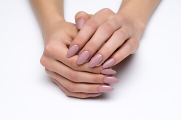 Wall Mural - Nude, beige gel extended manicure on sharp long nails close-up on a white background