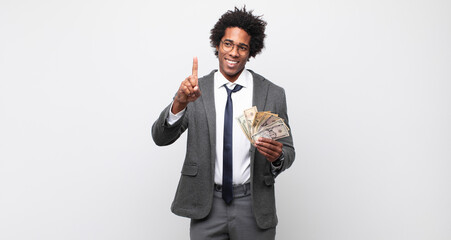 Wall Mural - young black afro man smiling proudly and confidently making number one pose triumphantly, feeling like a leader