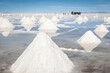 Horizontal view of infinite piles of salt in the Salar de Uyuni­. In the background -far away- workers load salt into a large truck, Bolivia