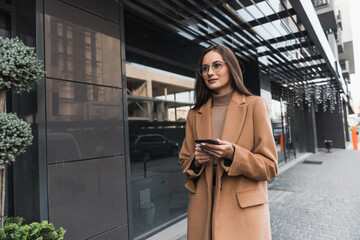 Wall Mural - Beautiful young business woman executive is using an application in her smart phone to check email or send a text message.