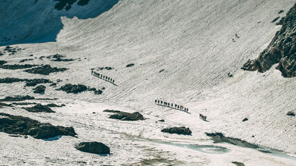 Group of tourists on the background of snowy mountains and blue lake