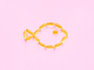 yellow omega 3 capsules with fish oil on a pink background