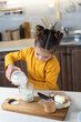 © Alex Desanshe - Baby girl pours milk into a glass in the home kitchen. Daughter holding a bottle from the farmer's soy milk in the evening the room in slow motion