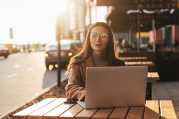 Wall Mural - Beautiful business woman working on laptop outside her office, freelance concept. Young attractive business woman sitting on the stairs and using modern laptop.