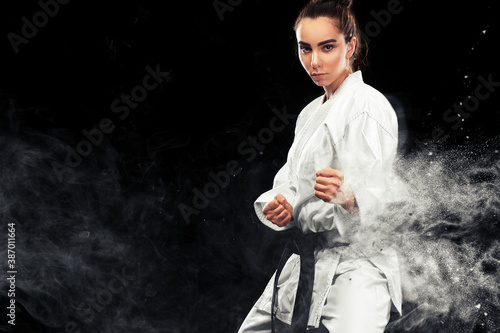 Portrait of sporty karate and taekwondo woman in white kimono with black belt on dark background Fototapet