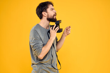 Poster - Male photographer with professional photo camera. Professional Creative approach studio yellow background