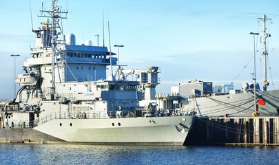 Canvas Print - Large military ship moored to a pier in Kiel, Germany. Nautical vessel, transportation, special equipment, industry, international security  and global communications concepts