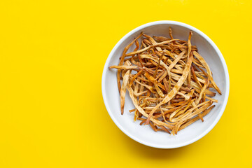 Dried Lily Buds on white bowl on yellow background.