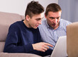 © JackF - Adult male with his son are resting together and playing on laptop at the home.