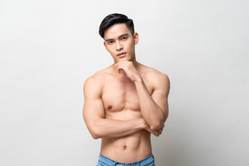 Shirtless handsome Asian man posing with hand touching chin on isolated gray background