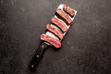 Wall Mural - Different degrees of roasting steak on a meat knife on a stone background