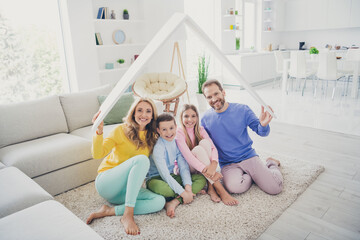 Poster - Full size photo of harmony family sit floor mom dad hold paper card roof above two little kids girl boy in house indoors