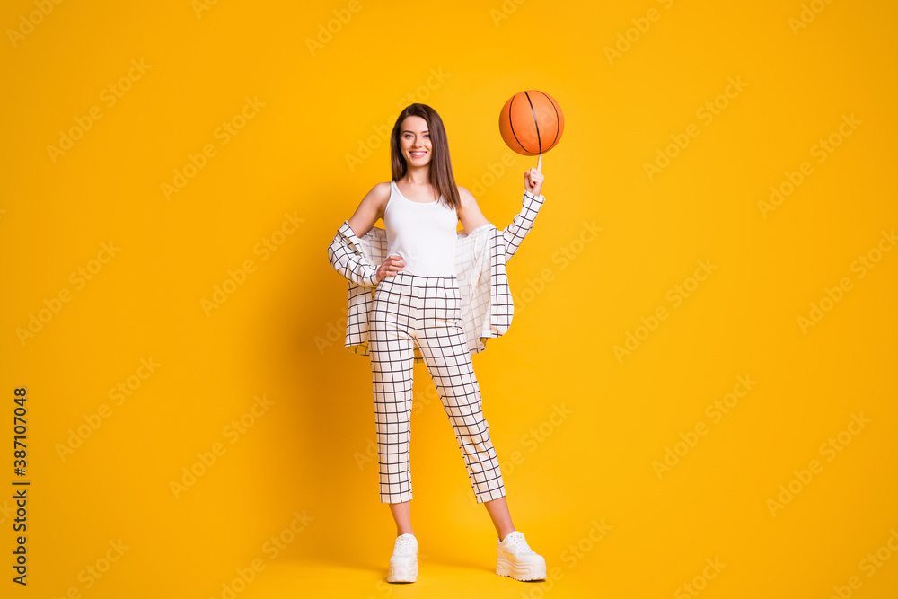 Photo of nice attractive sportive brown hair woman spinning ball playing basketball isolated over bright yellow color background - obrazy, fototapety, plakaty 