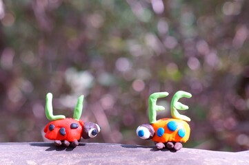 Wall Mural - Two figures of ladybirds made of plasticine. Next to it is the inscription life.