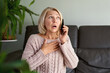 © JENOCHE - woman in a phone call sitting on a sofa in the living room in a house