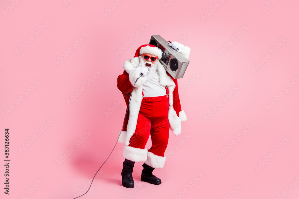 Full length photo cool crazy grey white hair beard santa claus big belly sing x-mas christmas eve noel song hold boom box mic wear suspenders cap sunglass isolated pink color background - obrazy, fototapety, plakaty 