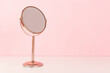 Gold mirror on pink background. Vanity table concept. Minimal composition. Copy space for your text.