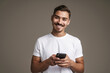 © Drobot Dean - Image of joyful unshaven guy smiling and using cellphone
