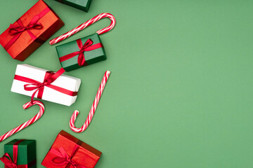 Wall Mural - top view of colorful gift boxes and candy canes on green background with copy space