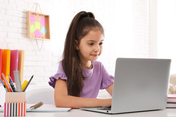 Canvas Print - Pretty preteen girl doing homework with laptop at table