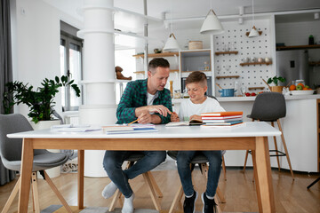 Father helping his son with homework at home. Little boy learning at home..