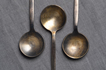 Ancient metal tablespoons on grey fabric close-up