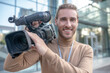 © zinkevych - Smiling cameraman holding camera on his shoulder outside